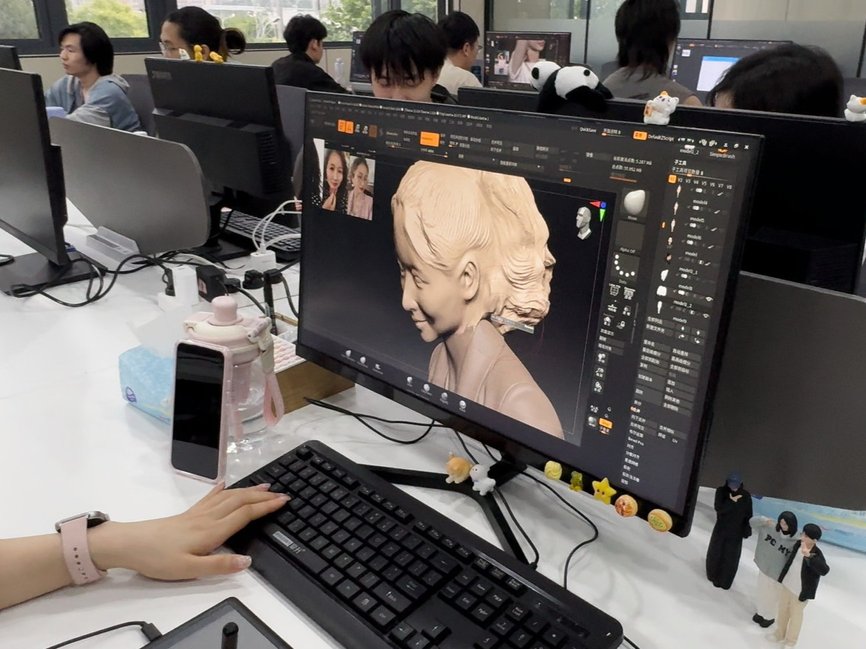 Close-up of a 3D figurine portrait model being sculpted on a workstation